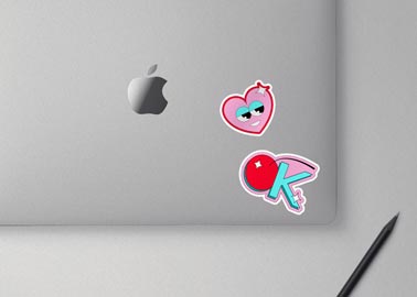 Two Stickers on a MacBook with a Pencil