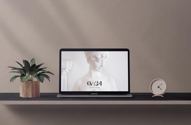 MacBook on a Desk with a Plant and a Clock