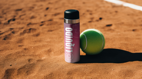 Thermos et balle de tennis sur le sable