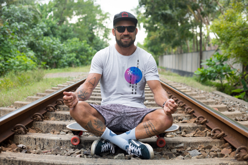 Мужчина улыбается и сидит на железнодорожных путях