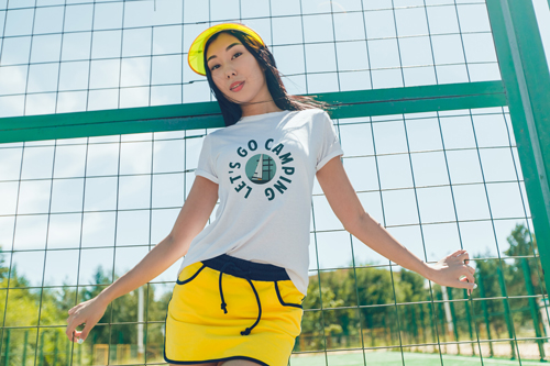 Girl in a T-shirt Standing at the Net Fence