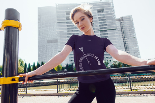 Femme en t-shirt posant contre des bâtiments